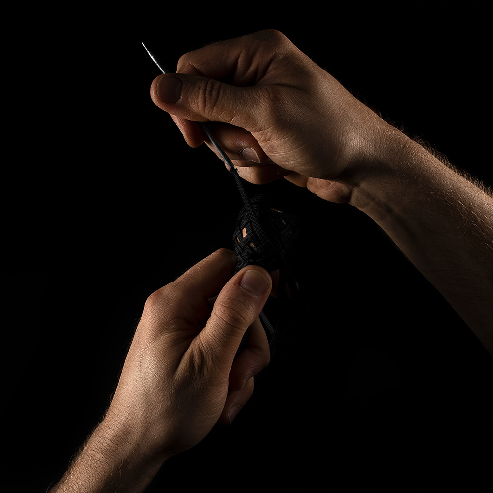 Close-up of hands working with needle and paracord